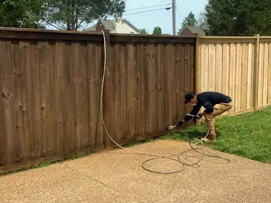 SafeGuard crew member spray-staining a wood privacy fence