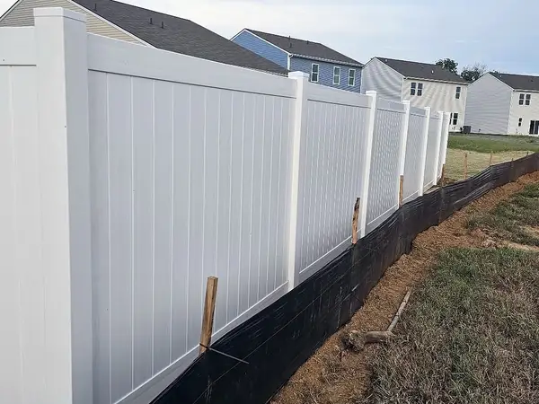 White vinyl privacy fence along a sloped yard